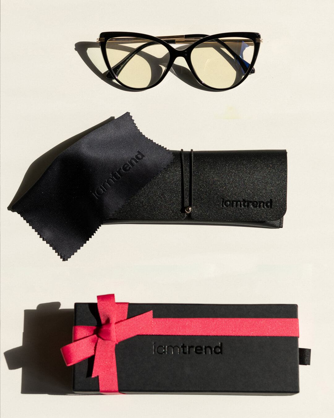 flat lay of cat-eye blue light blocking glasses with black frames, cleaning cloth, protective case and gift box