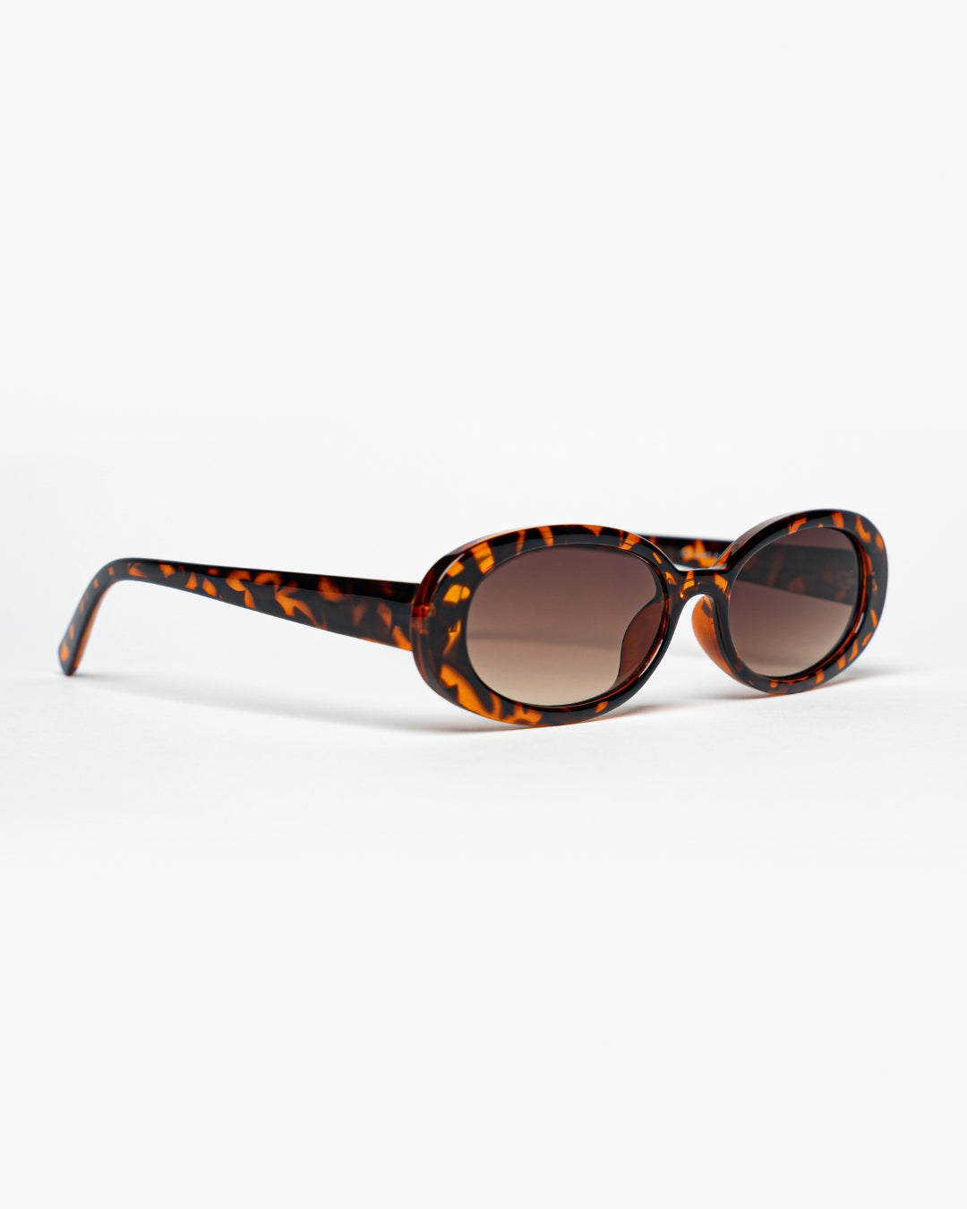 side view of slim oval sunglasses with tortoiseshell frames and brown gradient lenses