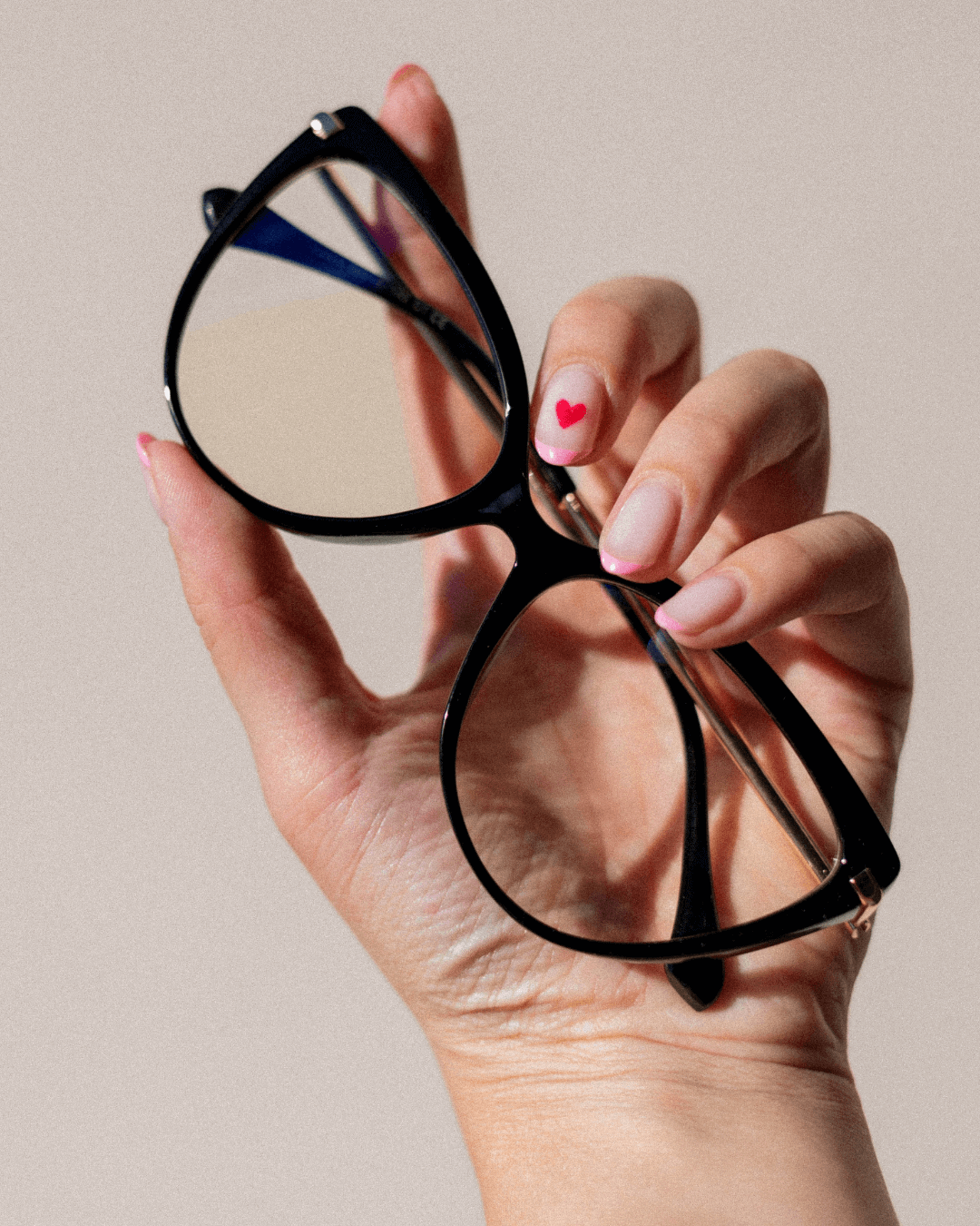 cat-eye blue light blocking glasses with a black frame and gold temples held in hand